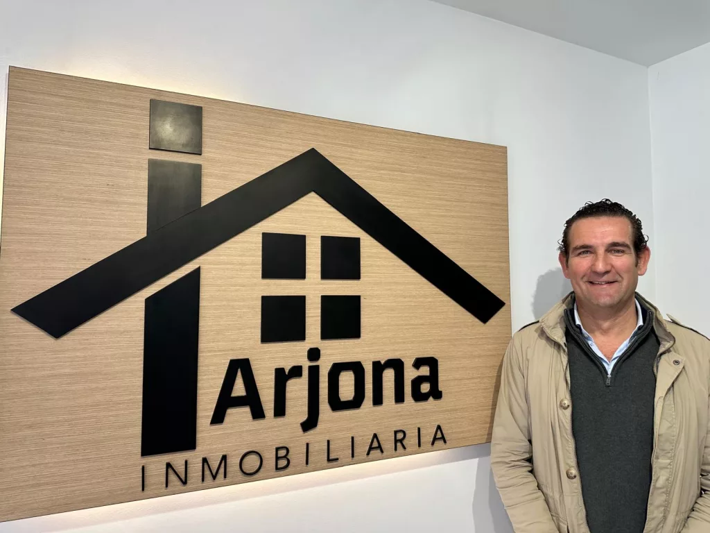Juan Alberto Arjona frente un cartel de madera en Inmobiliaria Arjona, Inmobiliaria en Lucena