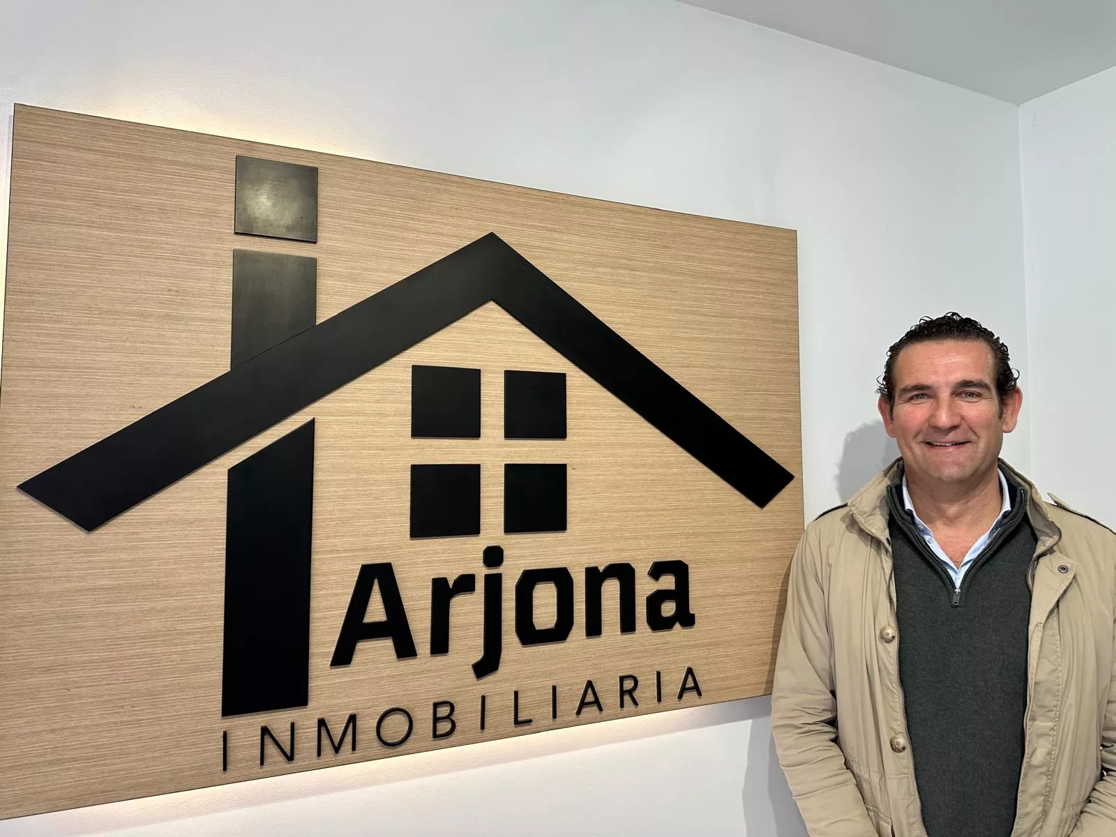 Juan Alberto Arjona frente un cartel de madera en Inmobiliaria Arjona, Inmobiliaria en Lucena